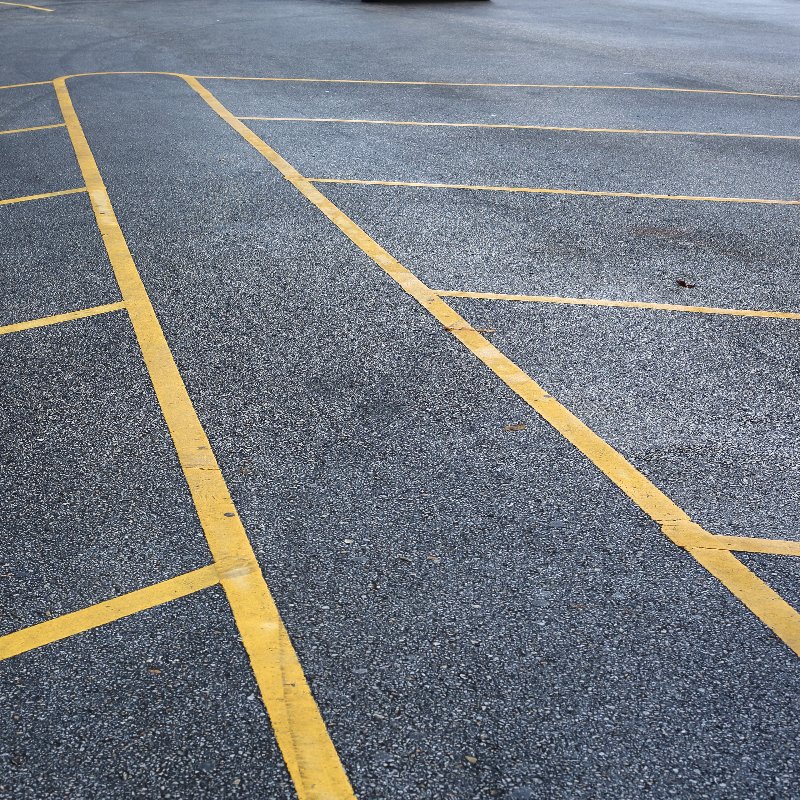 an empty parking lot with yellow marks on the pavement
