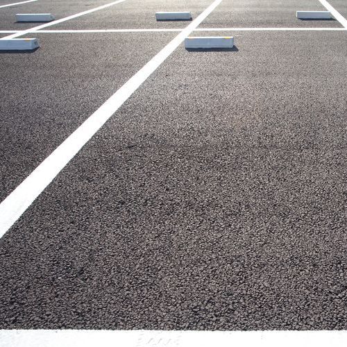 A Picture of an Empty Parking Space in an Asphalt Parking Lot.